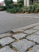 Foto: Hochstehendes Bordfragment mit Sturzgefahr im Kurvenbereich des Radwegs an der Drogerie 