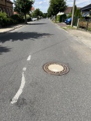 Foto: Fahrbahn und Abwasserdeckel beschädigt  